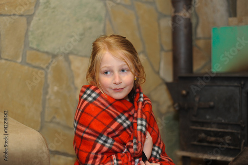 cute caucasian blonde girl sitting near russian fireplace, portrait