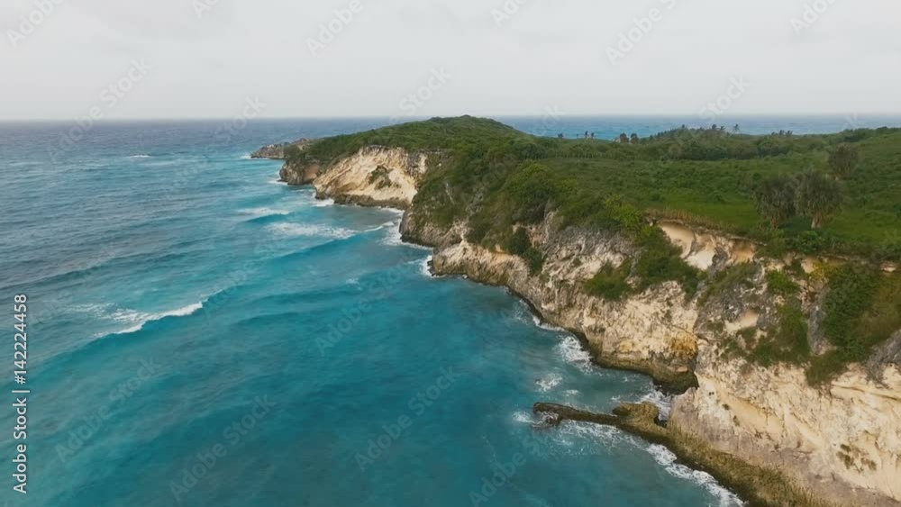 The sea waves are beating against grass-covered rocks in the daytime The sea waves are beating against grass-covered rocks in the daytime