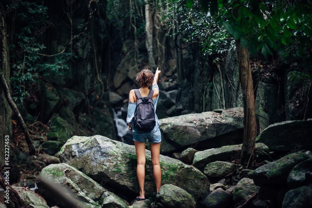 Back view of young woman with backpack in tropical jungle Back view of young woman with backpack in tropical jungle