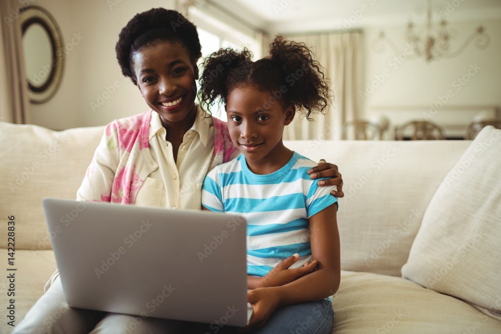 Portrait of mother and daughter using laptop in living room Portrait of mother and daughter using laptop in living room