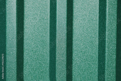 Green metal profiled sheets surface, under the sunlight.