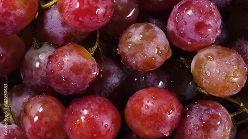 Excellent top view of grapes close up, water sprinkling and rotating against the clock. Vibrant flat lay of yummy fruit dessert with amazing texture in great 4k clip. Eco product for healthy food.