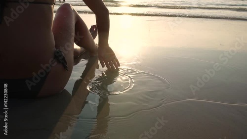 Close-up of female hand which plays with the wet sand on exotic beach. Slow motion