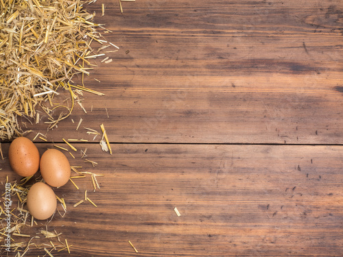 Rural eco background with brown chicken eggs and straw on the background of old wooden planks. The view from the top. Creative background for Easter cards, menu or advertising