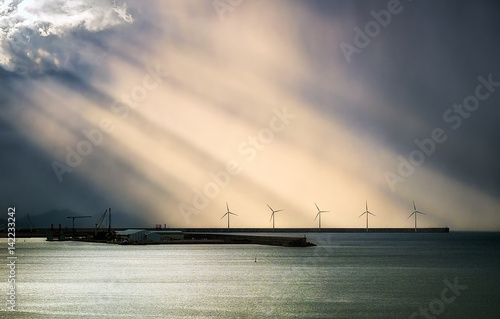 windmill on sea with sun rays photo