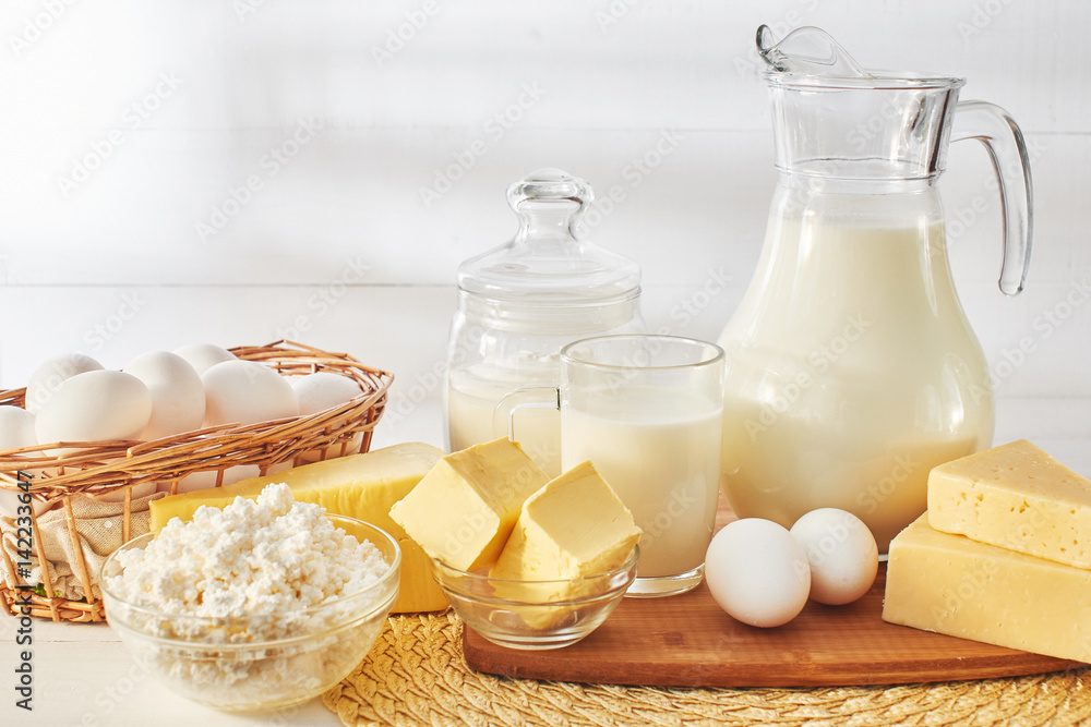 A set of products consisting of milk, butter, curd, cheese and eggs on white wooden table A set of products consisting of milk, butter, curd, cheese and eggs on white wooden table
