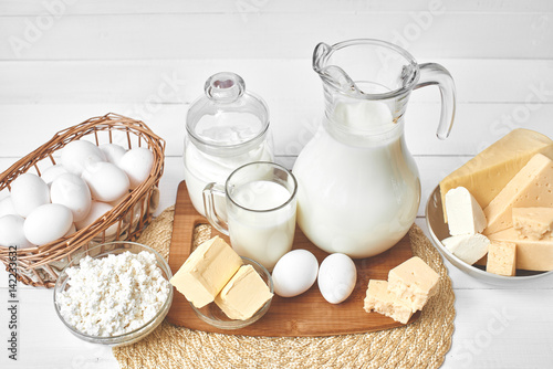 A set of products consisting of milk, butter, curd, cheese and eggs on white wooden table