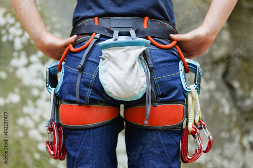 Female Climber with climbing equipment on the belt is ready to make her way up. Extreme sport