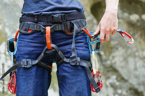 Female Climber with climbing equipment on the belt is ready to make her way up. Extreme sport