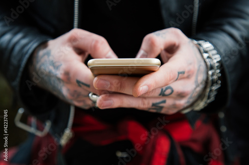 Tattooed man hands with smartphone