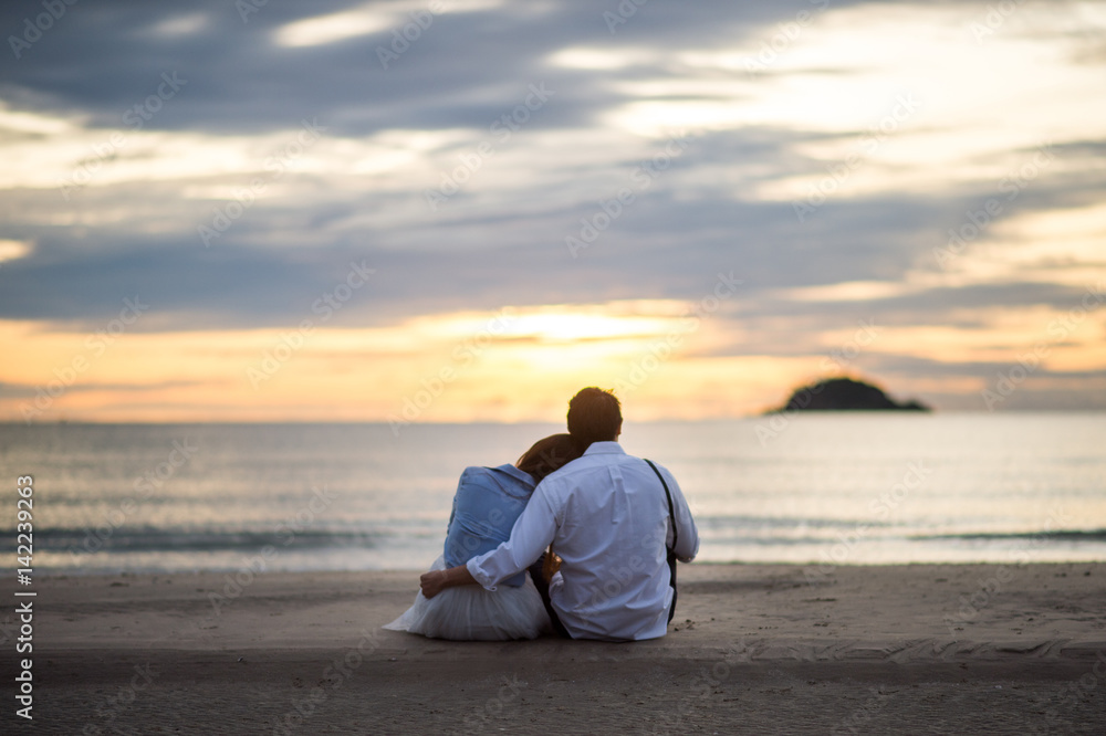 Couple watching sunset in the beach romantic scene