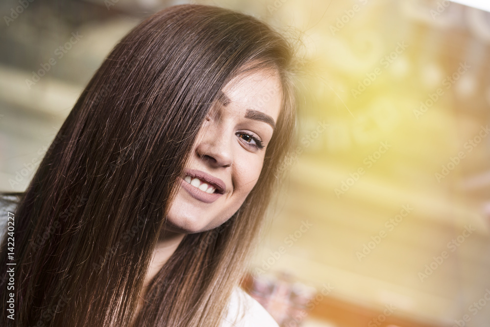 Fototapeta premium Close-up of a beautiful brunette. Portrait of a young gorgeous woman. Lensflare in background.