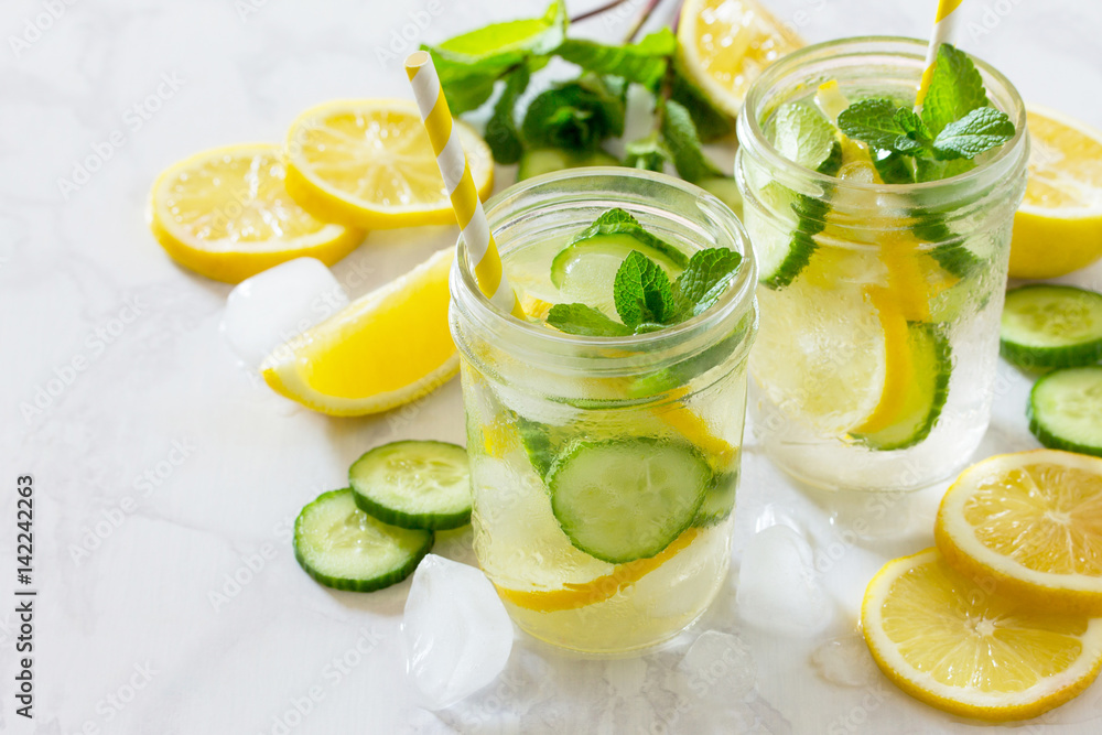 Refreshing summer drink with lemon and cucumber on a background of stone. The concept of eating vegetarians, fresh vitamins, a homemade refreshing fruit drink. Refreshing summer drink with lemon and cucumber on a background of stone. The concept of eating vegetarians, fresh vitamins, a homemade refreshing fruit drink.