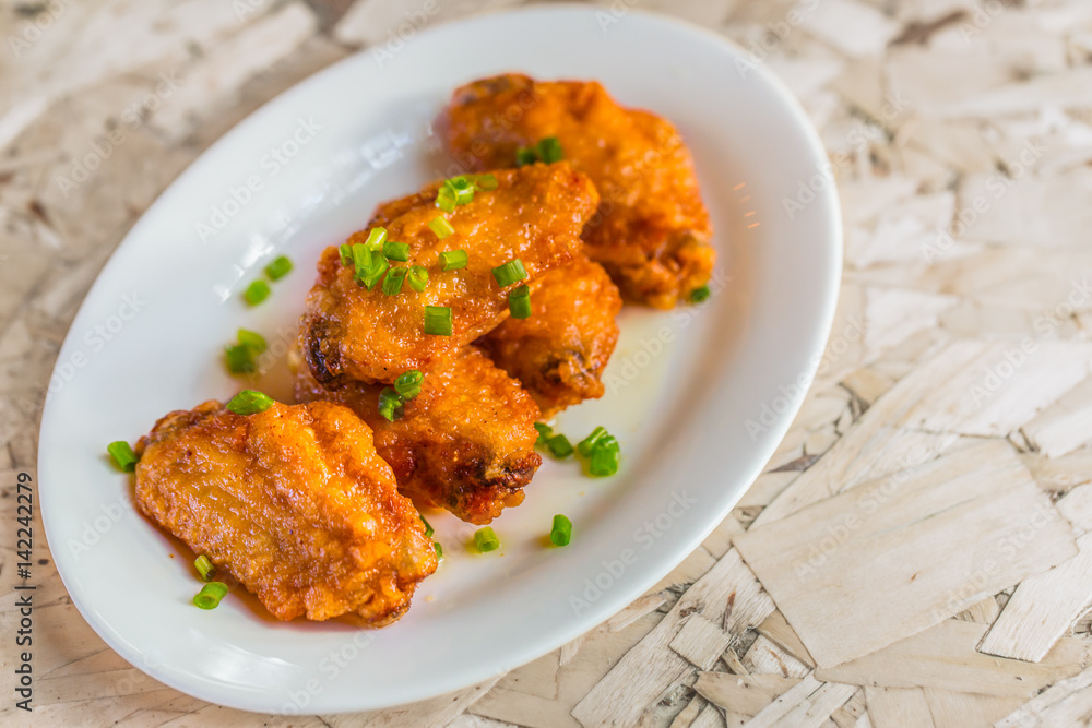 Spicy Deep Fried Chicken Wings menu on served dish with wood table. Spicy Deep Fried Chicken Wings menu on served dish with wood table.