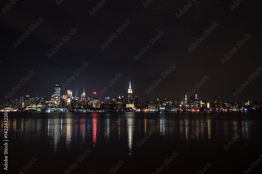 Midtown and Downtown Manhattan Lit Skyline Reflecting in the Hudson at Night as Seen from Newport Green Park in Jersey City, USA