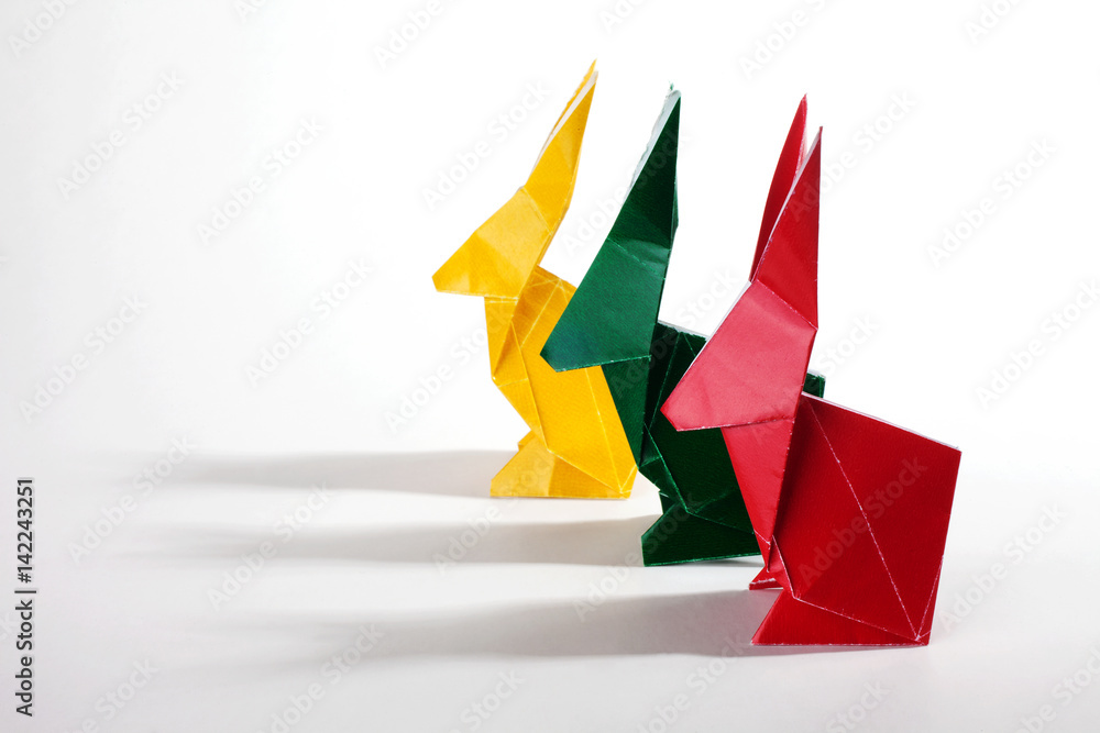 Naklejka premium Colored origami rabbits over a white background