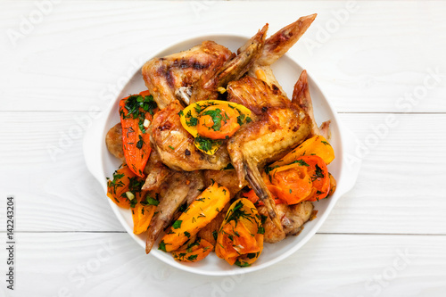 Grilled chicken wings, with vegetables. Wooden white table. 