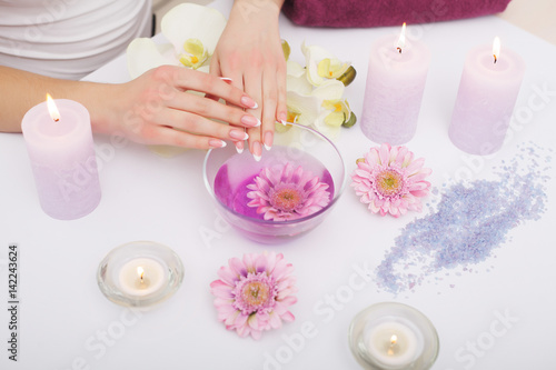 Spa Manicure. Woman Hands With Perfect Natural Healthy Nails Soaking In Aroma Hand Bath. Closeup Of Glass Bowl With Water And Blue Sea Salt For Spa Procedure. Professional Nail Care. High Resolution