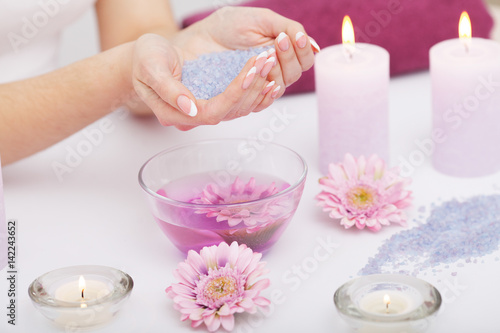 Spa Manicure. Woman Hands With Perfect Natural Healthy Nails Soaking In Aroma Hand Bath. Closeup Of Glass Bowl With Water And Blue Sea Salt For Spa Procedure. Professional Nail Care. High Resolution