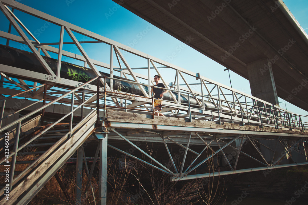 young man running over metal bridge