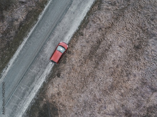 Red car on country road in spring time. Aerial view.