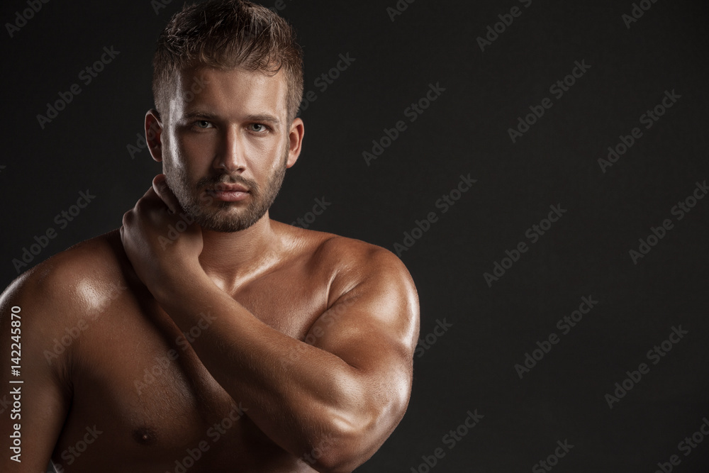 Model man with an open  chested on a dark background , muscular body of a young man in jeans . Shot in a studio .