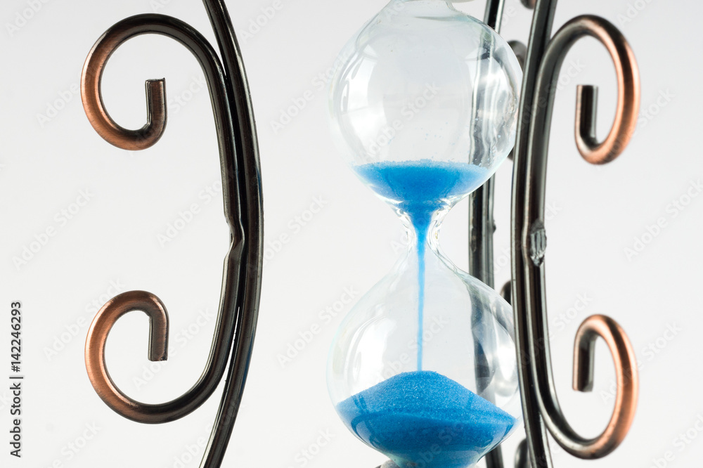 Fototapeta premium Vintage hourglass with curls patterns on the edges. Presuposes (perespevshie) blue sand in them.