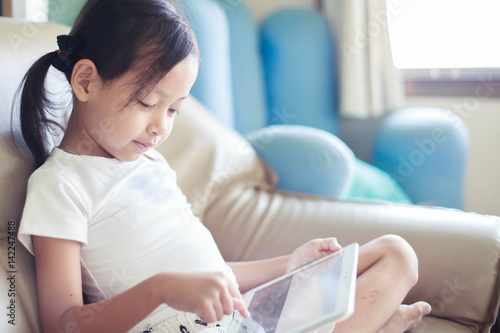 little child girl playing tablet at home.