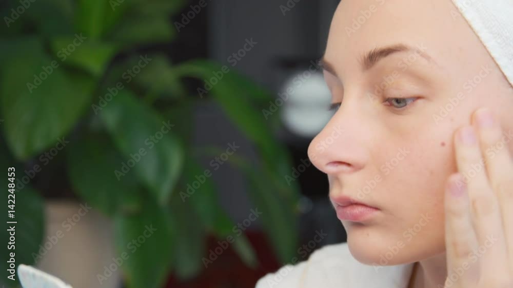 Beautiful young woman applying cream on face. Beautiful young woman applying cream on face.