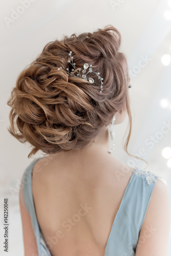 beautiful volume hairstyle for a bride in a gentle blue light dress with large earrings and adornment in hair