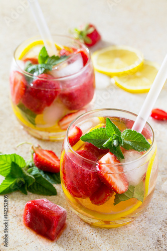 A refreshing summer drink with ice and strawberries on a stone background. The concept of eating vegetarians, fresh vitamins, a homemade refreshing fruit drink.