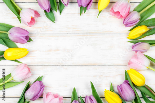Bunch of pink and yellow tulips on a white wooden background