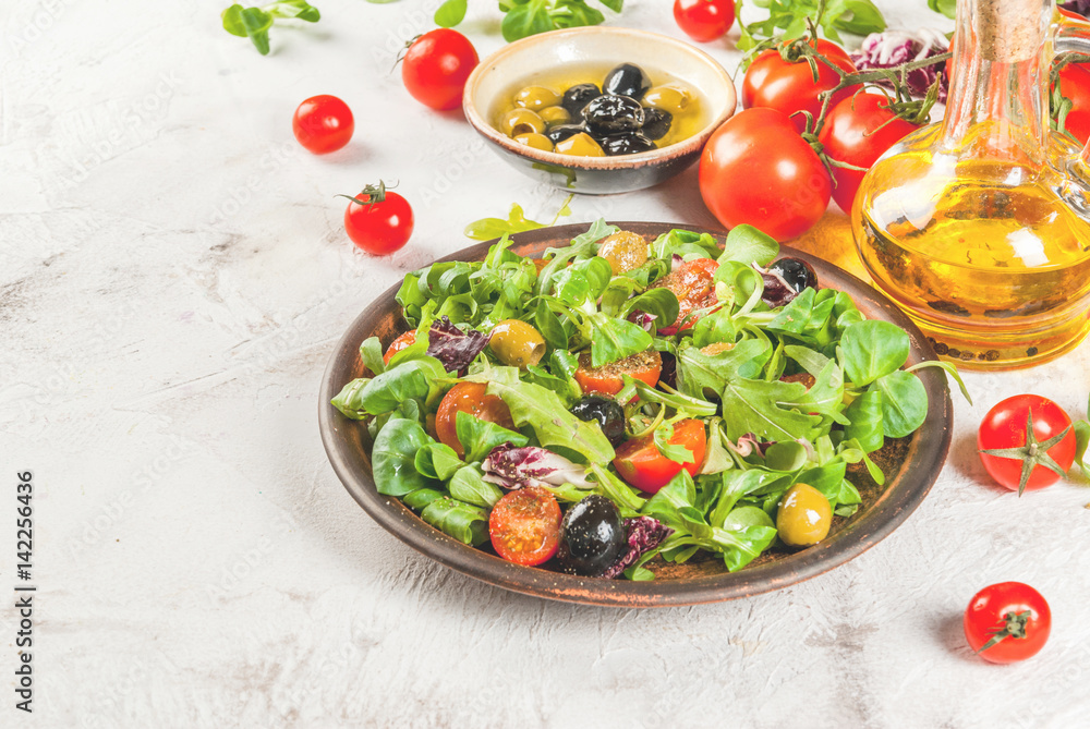 Italian Cuisine. Spring vegan diet food. Fresh lettuce, greens, tomatoes, green and black olives. With fresh organic home-made oil, raw ingredients on the table. Copy space Italian Cuisine. Spring vegan diet food. Fresh lettuce, greens, tomatoes, green and black olives. With fresh organic home-made oil, raw ingredients on the table. Copy space
