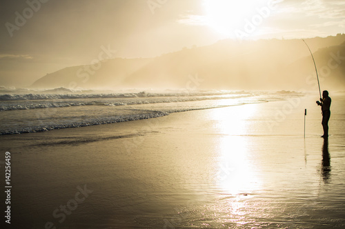 Fisherman with Fishing Rod Holder during Sunset at Wilderness Beach in South Africa