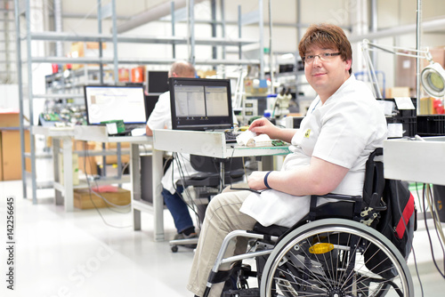 Rollstuhlfahrer am Arbeitsplatz in einer Fabrik zur Montage von Elektronik - Alltag mit Gehbehinderung // Wheelchair driver at the workplace in the industry