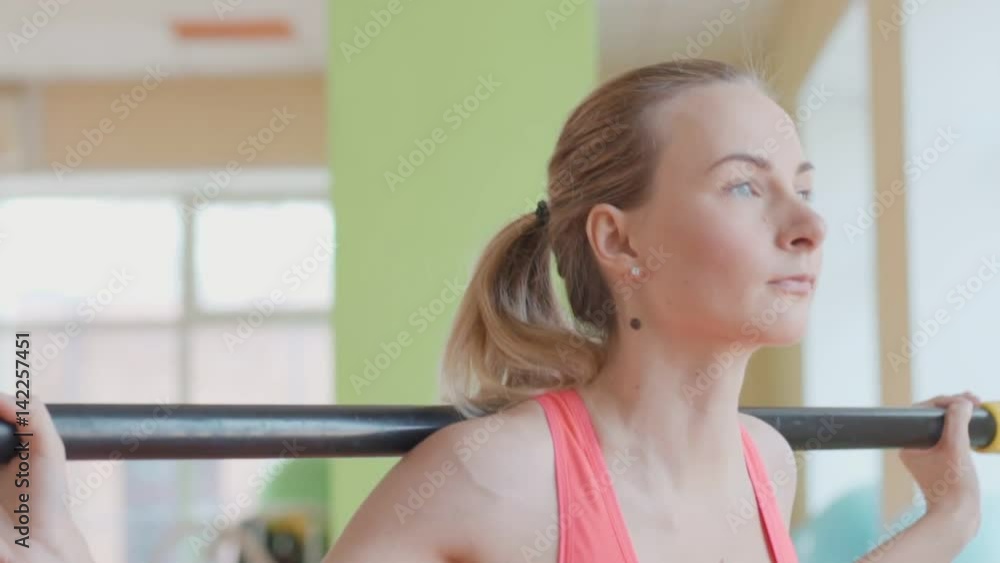 Side view portrait of a young woman doing squats at fitness gym Side view portrait of a young woman doing squats at fitness gym