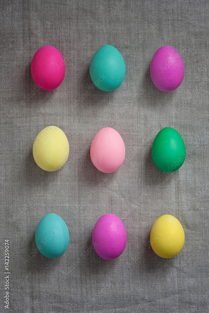 Pattern of Rows of colored easter eggs grey linen textured background. Easter web Background. Group of colored painted eggs. Happy Easter celebration concept. Template mock up with copy space for text