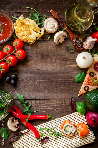 Frame made of vegetables, pizza, sushi rolls, pasta and sauce on wooden background. Flat lay. Food frame