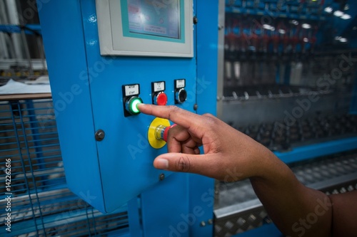 Hands of factory worker pressing a green button 