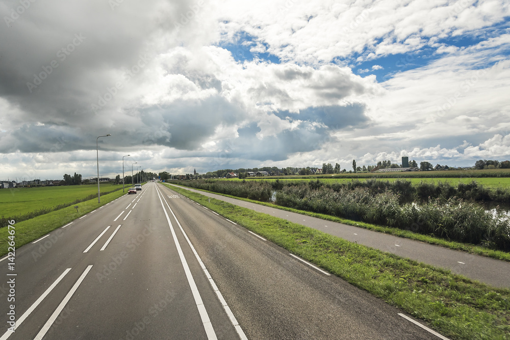 Fototapeta premium Country road with beautiful markings, against a contrasting cloudy sky.