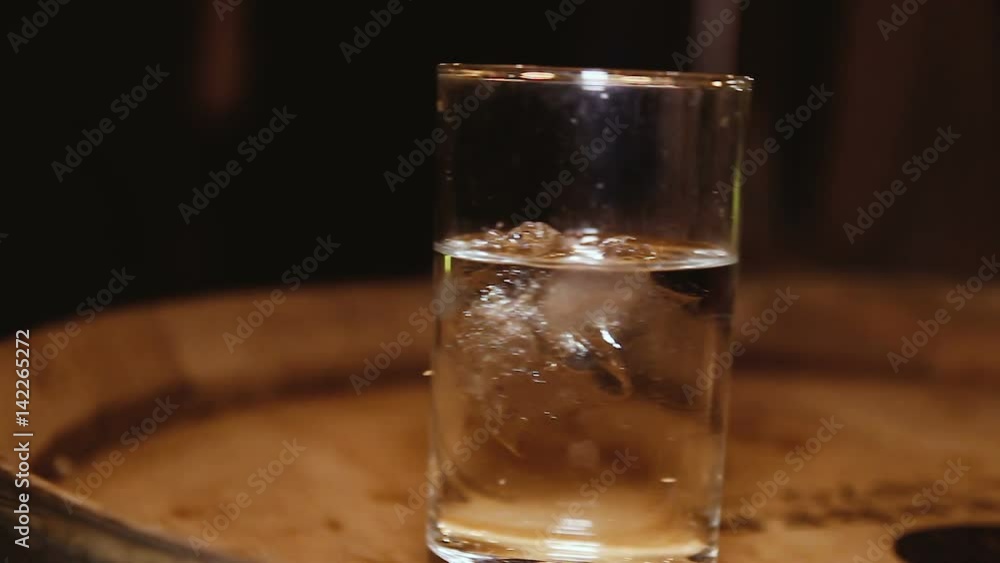 Glass of water with ice on a wooden barrel. Glass of water with ice on a wooden barrel.