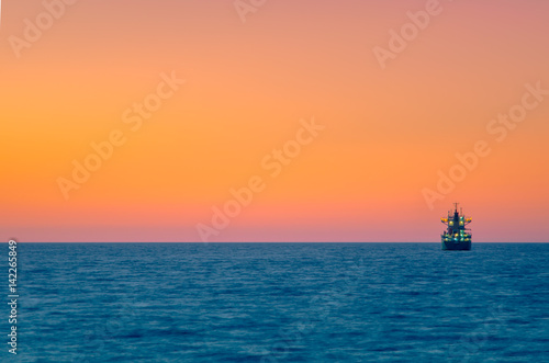 Cargo ship sailing during colorful sunset, Crete, Greece.