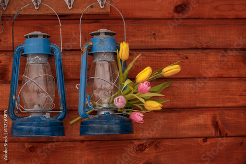 Two blue old kerosene lamps with bouquet of tulips on a wooden background
