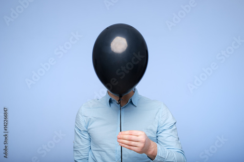 Photos A white man covers his face with a black balloon