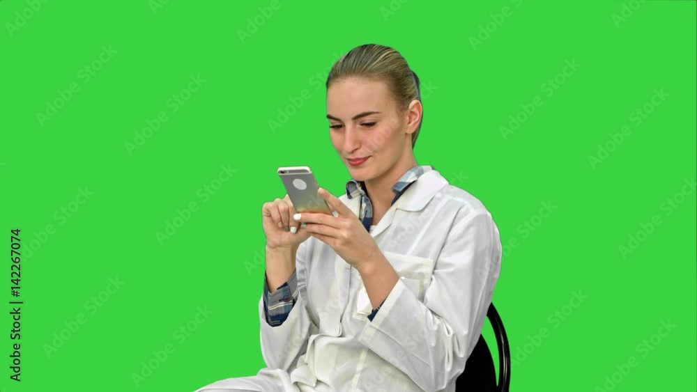Young woman surgeon doctor reading sms on cell phone on a Green Screen, Chroma Key. Young woman surgeon doctor reading sms on cell phone on a Green Screen, Chroma Key.