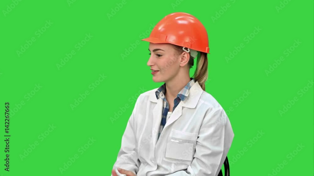 Female engineer in safety helmet sitting and talking on a Green Screen, Chroma Key. Female engineer in safety helmet sitting and talking on a Green Screen, Chroma Key.