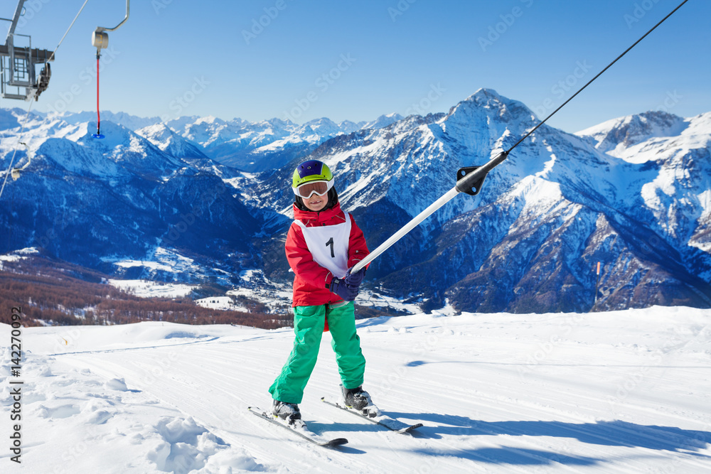 Little skier at surface lift against the mountains