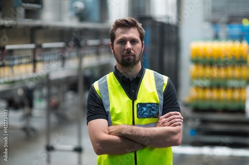 Factory worker standing with arms crossed in factory