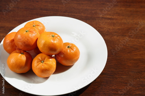 Fresh oranges on white plate in sunshine