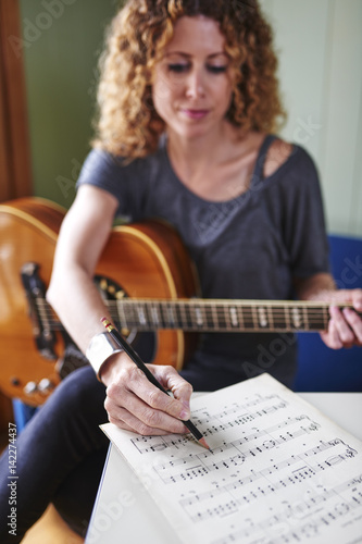 a young woman with a guitar, writing music.